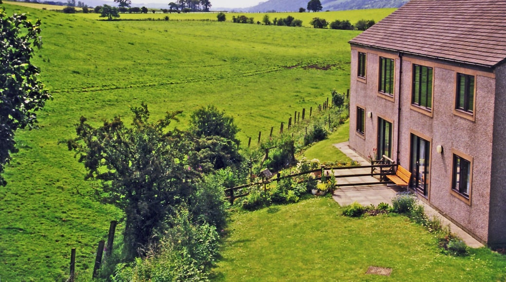 Site of former Hornby station, 1998. View westward, towards Lancaster: ex-Midland (Skipton etc.) - Wennington - Lancaster - Morecambe - Heysham secondary main line. The station was closed 16/9/57 (goods 20/4/64) and even the whole line Wennington - Lancaster (Green Ayre) - Morecambe was closed entirely 3/1/66, leaving a route round via Carnforth as access from Yorkshire to Morecambe and Heysham. Here in 1998 the route is barely recognisable and a modern house has been built where the station was once. The view is south of the village and down the Lune Valley with Crag Lot (1,529 ft.) over on the right.