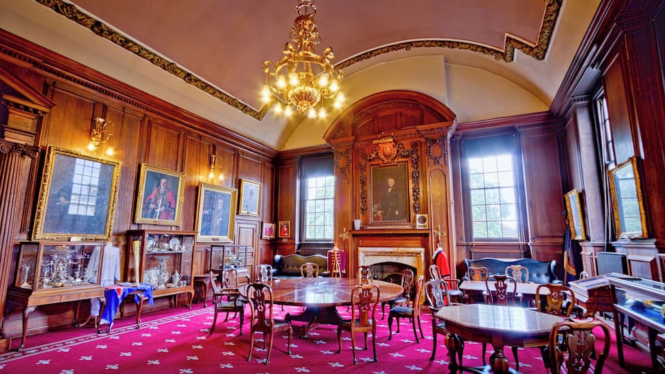 An ornate room with a large chandelier, wooden paneling, and a fireplace.