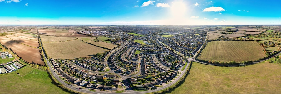 Vista aérea de una zona residencial con casas, calles y campos circundantes.