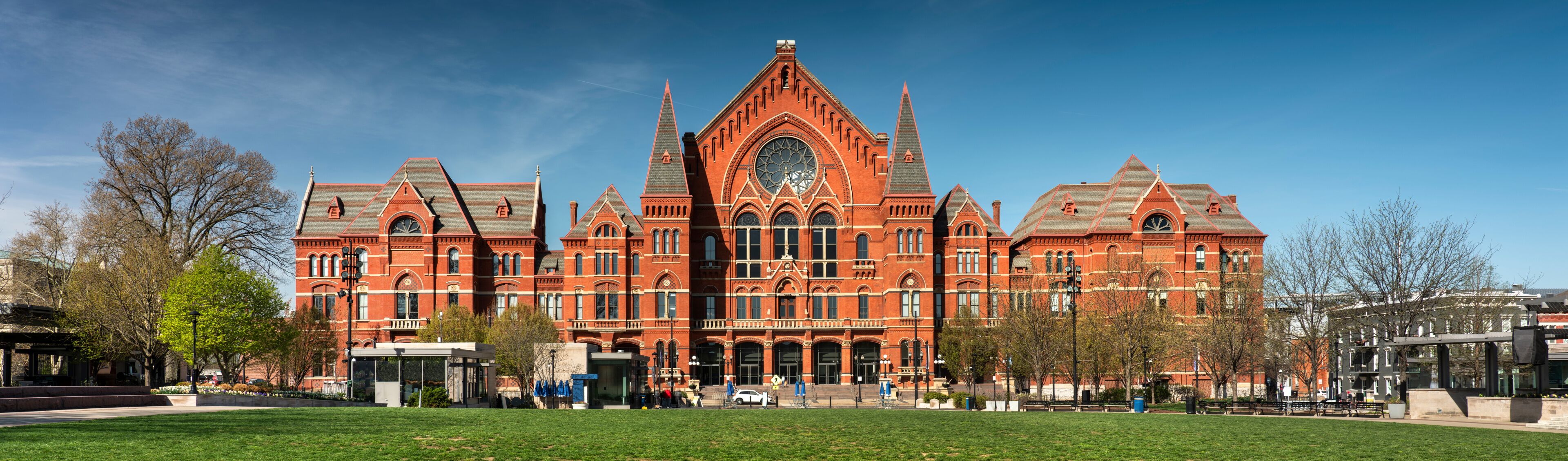 A large red brick building with a central clock tower and multiple spires.