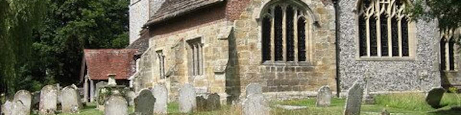 A historic church with a stone facade, a tower, and a cemetery with headstones.