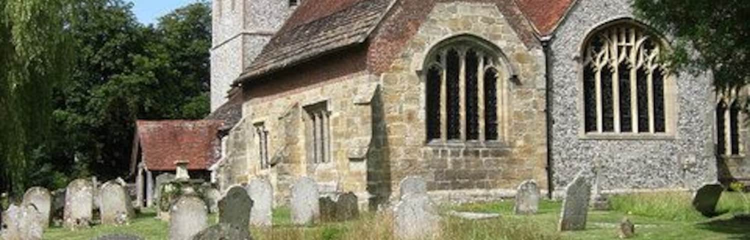 Una iglesia histórica con fachada de piedra, una torre y un cementerio con lápidas.