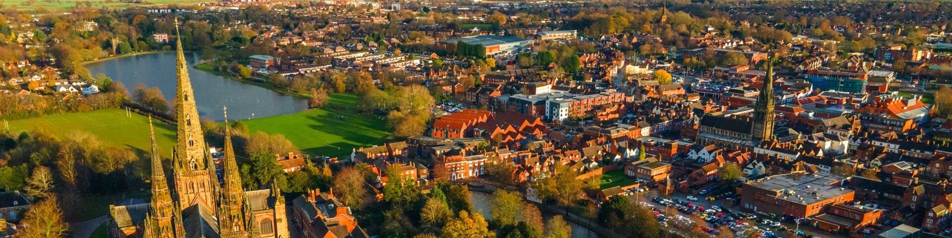 Lichfield Cathedral beside wide urban lake and green waterfront area