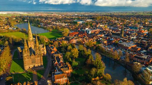 Lichfield Cathedral beside wide urban lake and green waterfront area