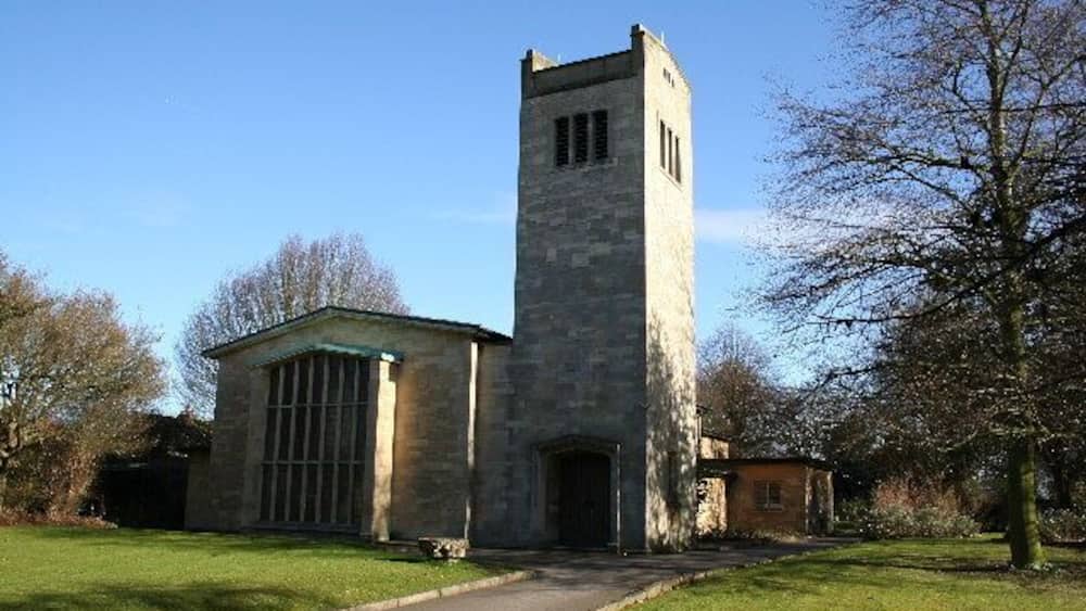 A stone church with a tall tower and a small adjacent building.