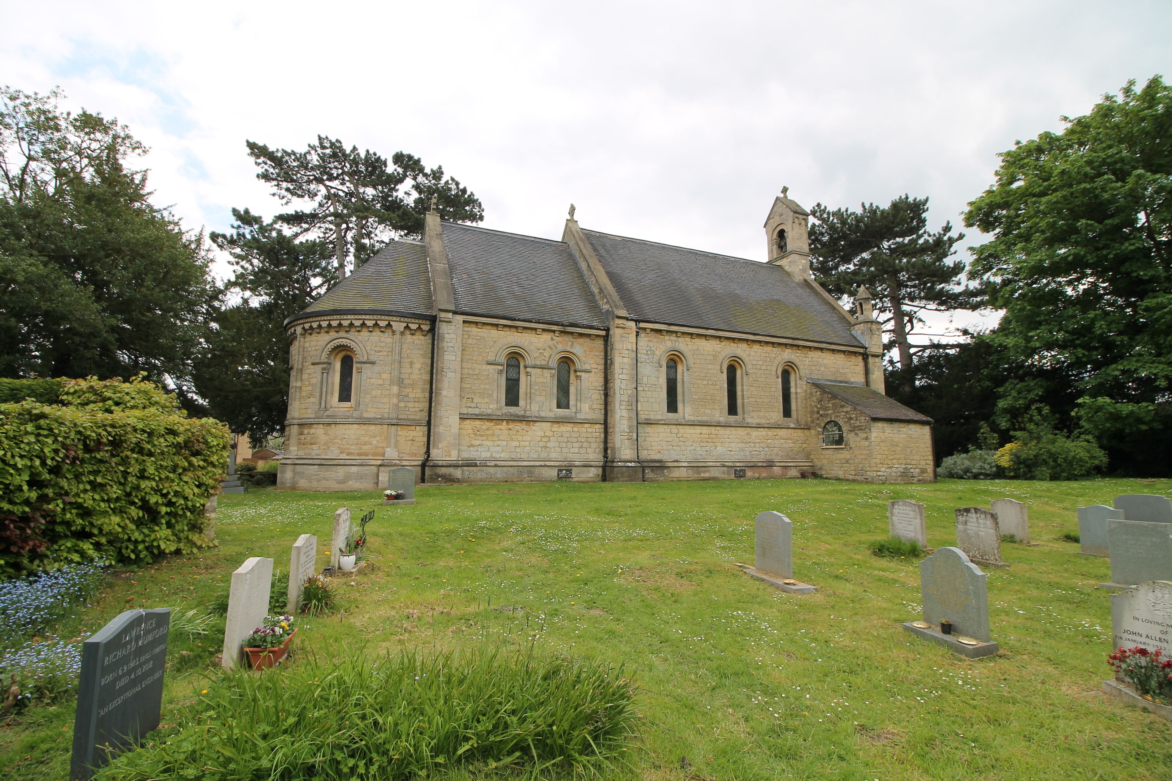 A stone church with a steeple, surrounded by a cemetery with headstones.