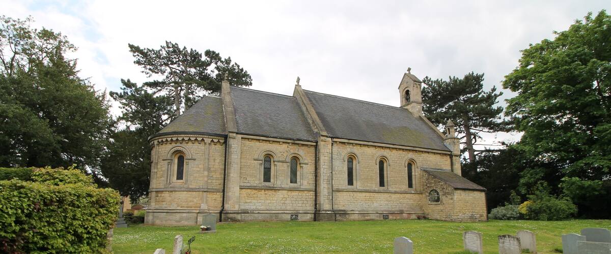 A stone church with a steeple, surrounded by a cemetery with headstones.