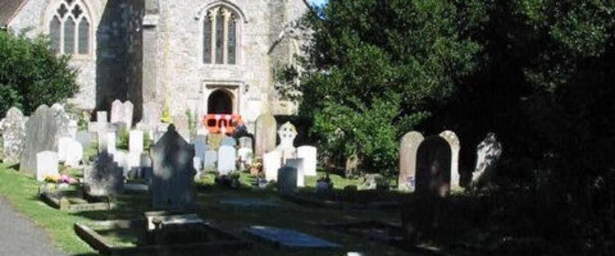 A church with a tall tower and a cemetery with gravestones.