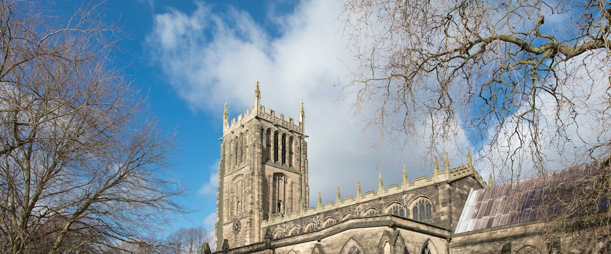 Une église historique dotée d’un haut clocher et de fenêtres en arc de cercle.