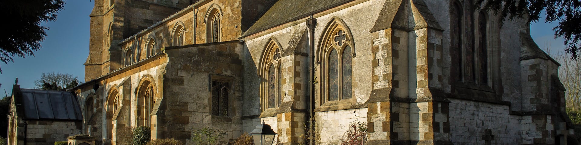 The church dates from the 13th century onwards. The nave was rebuilt in 1843, and the chancel in 1873 by Fowler. The church is built from ironstone with limestone dressings, with a slate and lead roof. There is a western tower with three bells, nave with clerestory, north and south aisles, chancel and south porch. The church originally consisted of tower, nave, chancel and south aisle only, and there is no record of any restoration before 1831. The four bay south arcade is early 13th century with circular piers. The north arcade is all 19th century. The nave roof is 19th century, but incorporates 15th C. carved wooden figures to the hammer beams. The ceiling has been elaborately decorated with roundels containing paintings of Saints. The words of the Te Deum are written around the walls of the chancel at the border with the roof, and the theme of the decoration relates to the first verse of the Te Deum. There is a fine sculptured stone reredos, painted and gilded. The organ is also painted and gilded by J.G. Smyth. All fittings are 19th century apart from the 15th century octagonal font. The 2 manual organ is by Nicholson of Worcester from 1904. Photo by J.Hannan-Briggs