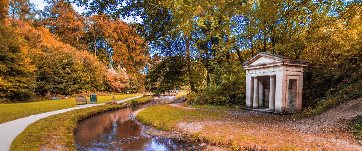 Ein Fluss, ein kleiner Tempel und Herbstbäume.