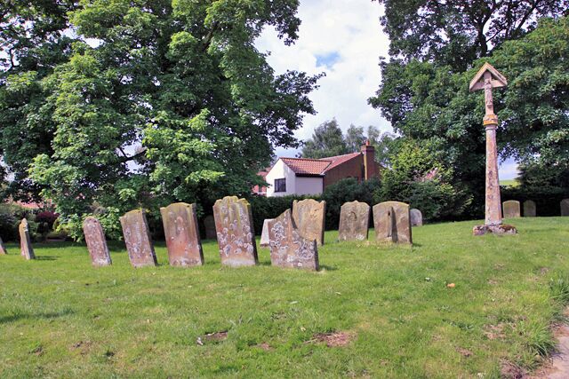 A grassy area with several standing stones and a tall stone cross.