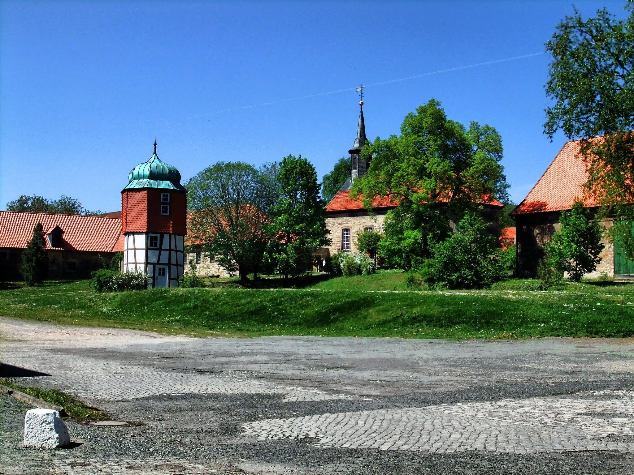 Ein historisches Gebäude mit rotem Ziegeldach, einer grünen Kuppel und einem hohen Turm.