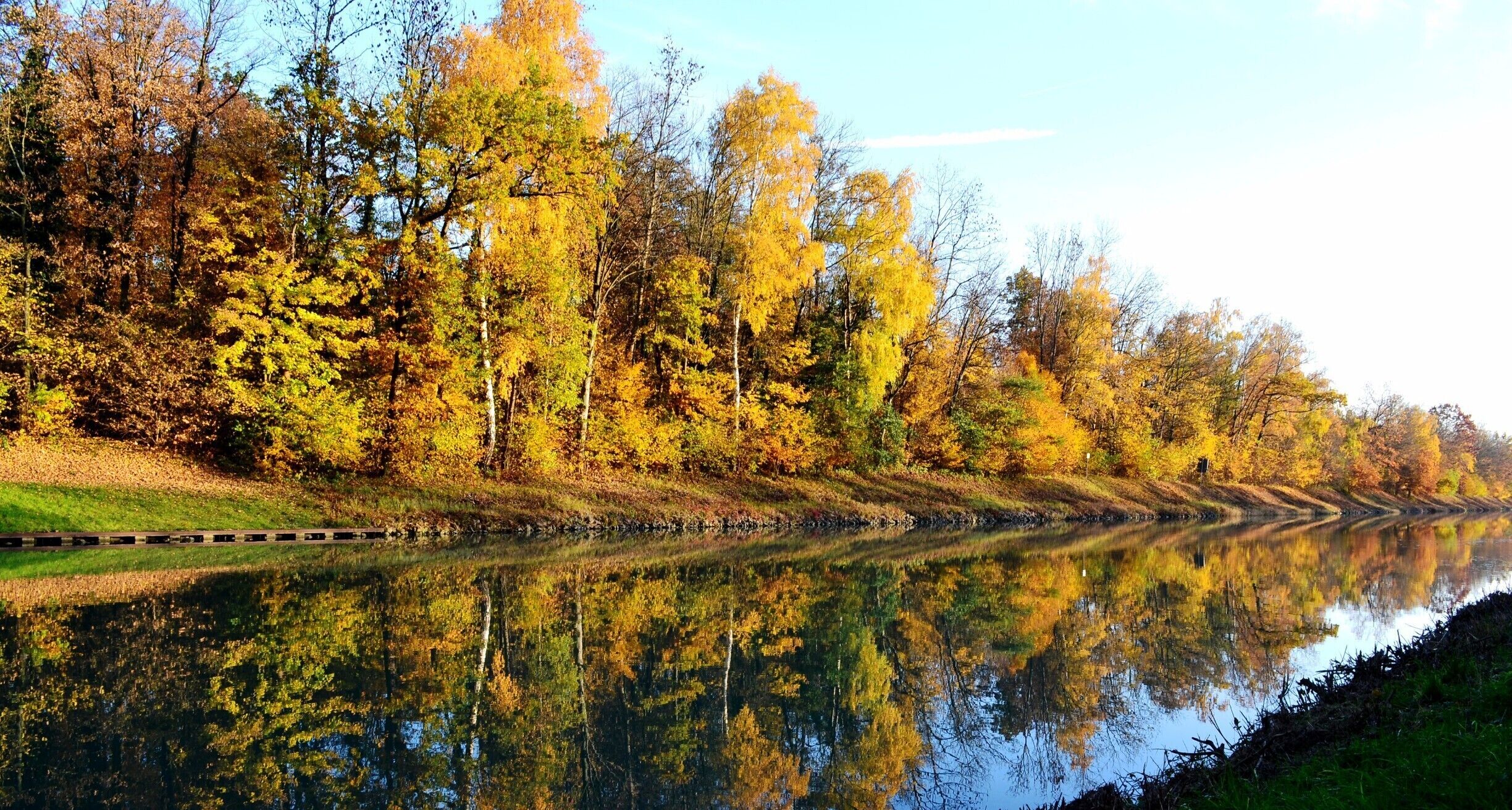 A calm river reflecting autumn trees.