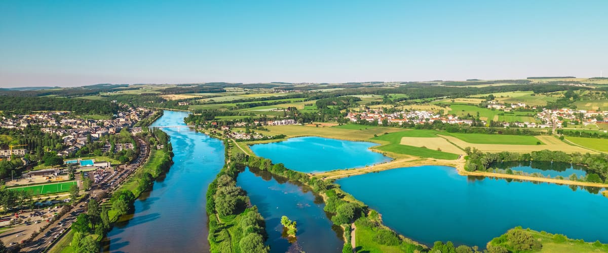 A river winding through a town with green fields and a large body of water.