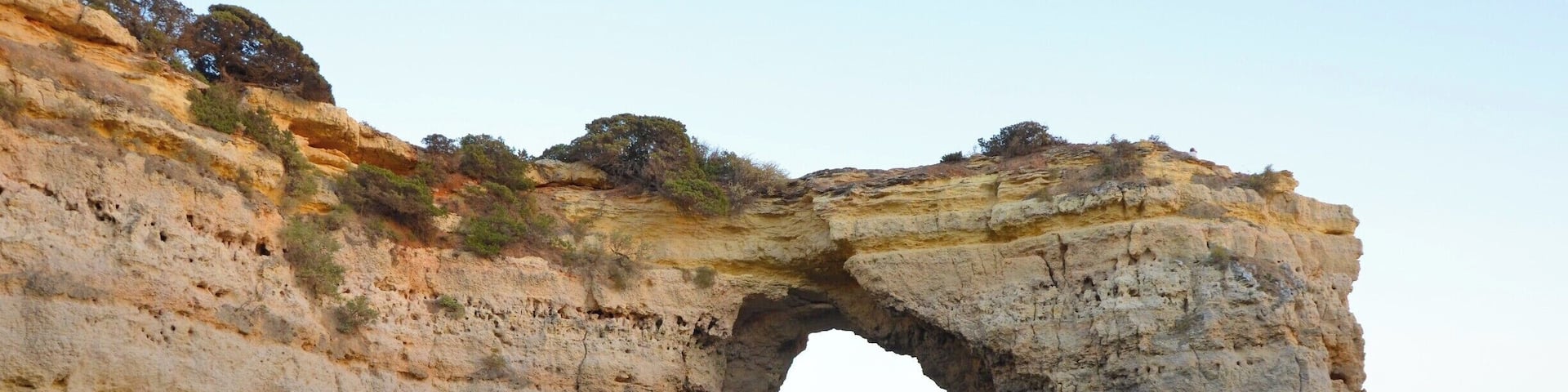 The sun is about to set as a small rowboat comes to the little Portuguese beach alcove. The day's last rays reflect off the stone cliffs.
#instone