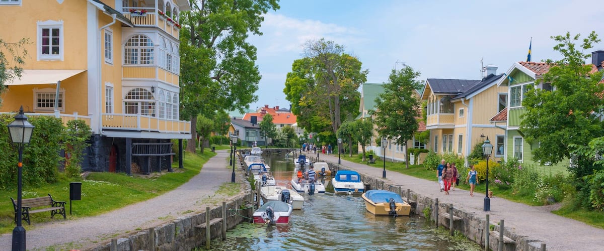 A canal with boats, a pedestrian path, and colorful buildings.