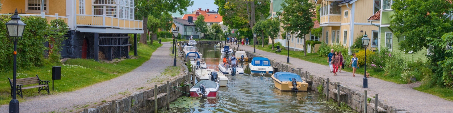 A canal with boats, a pedestrian path, and colorful buildings.