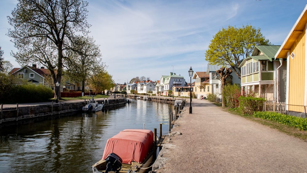 A canal with boats, a row of houses, and a clear sky.
