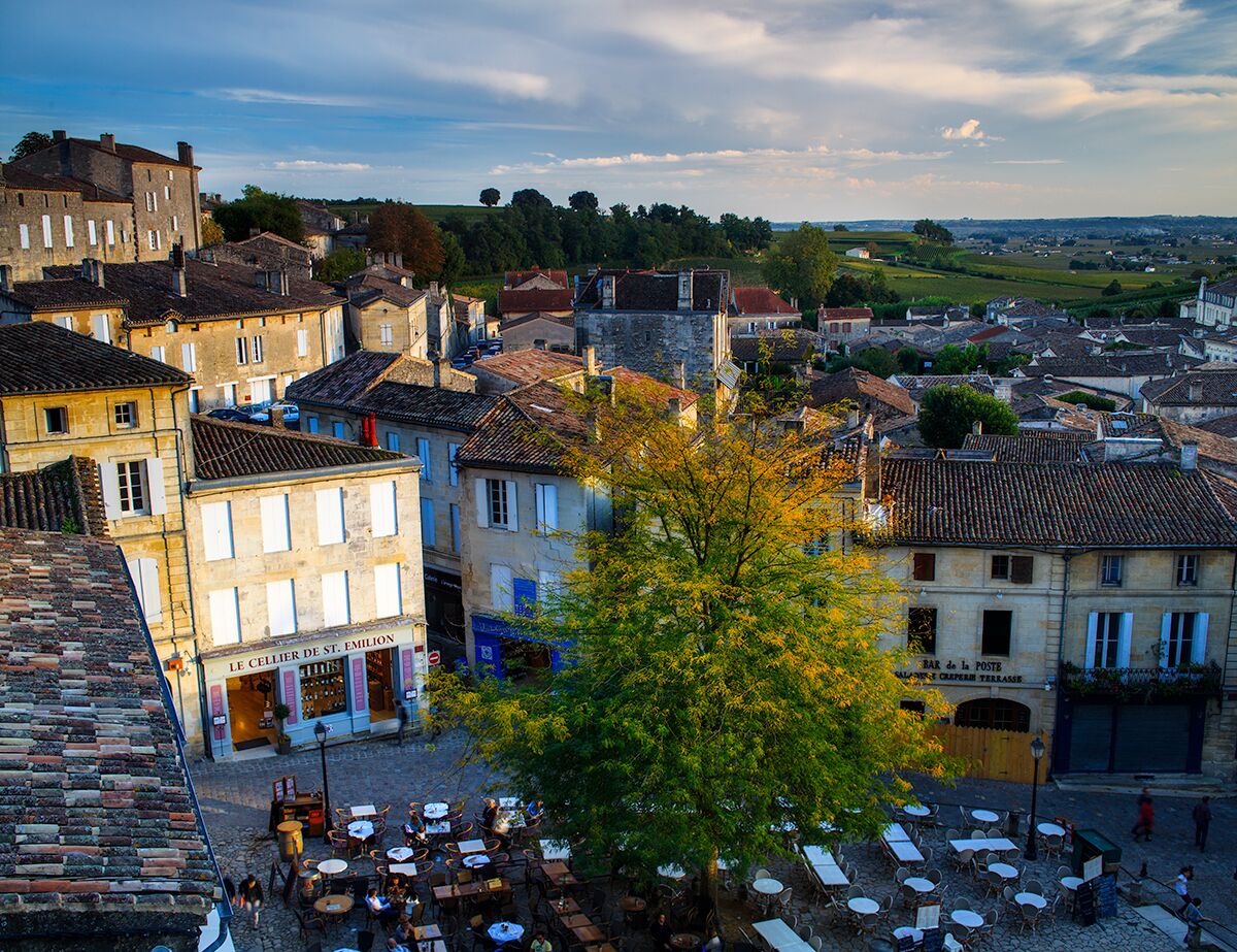 A historic town with cobblestone streets, traditional buildings, and a café area.