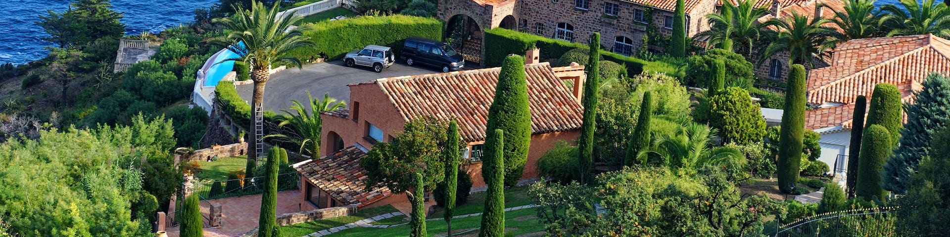 A coastal estate with a large house, a swimming pool, and a view of the sea.