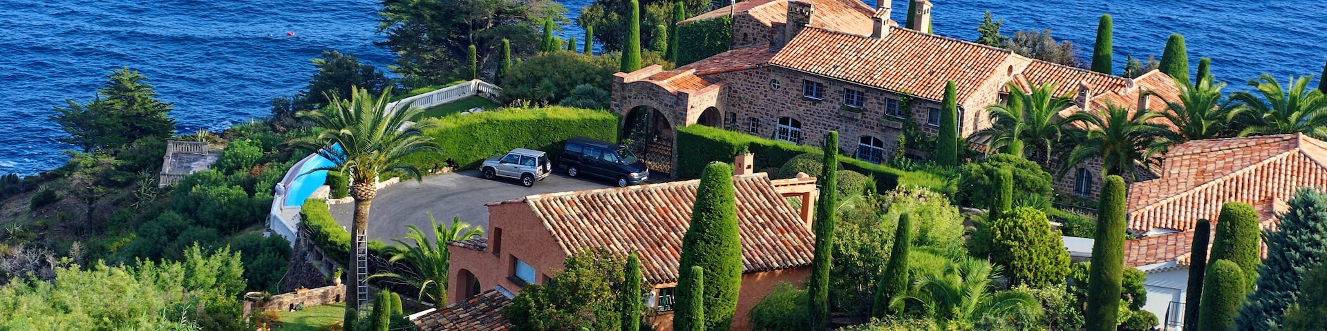 Una propiedad costera con una casa grande, una piscina y vista al mar.
