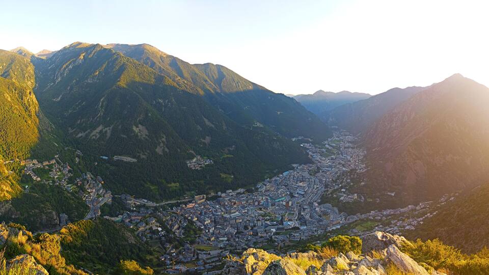 A mountainous landscape with a valley town surrounded by forested hills.