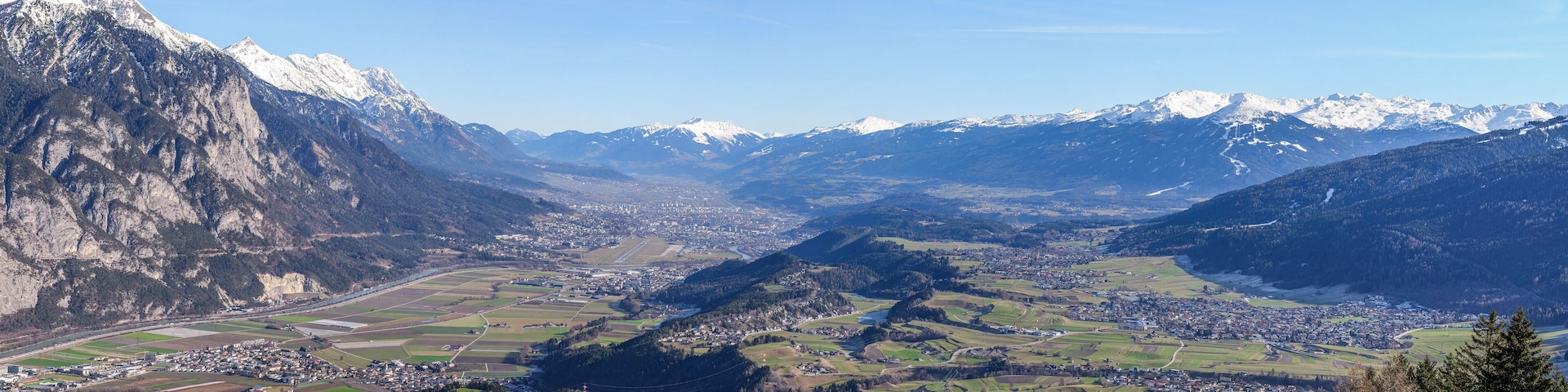 A valley with mountains, a town, and fields.