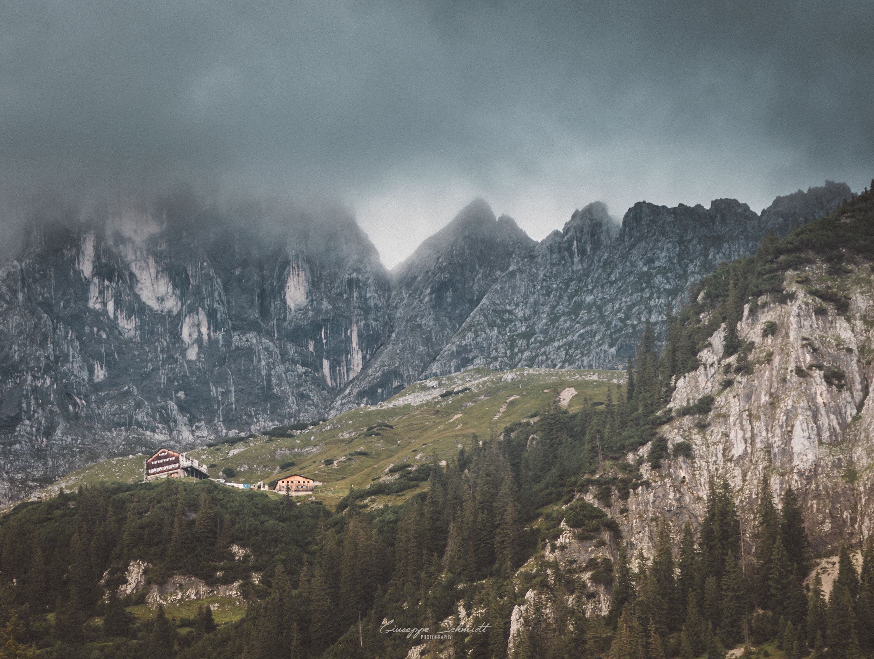 A mountain landscape with a chalet and a forested valley.