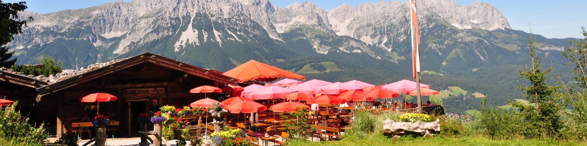 Un restaurante de montaña con sombrillas rojas y un asta de bandera.