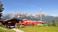 Un restaurante de montaña con sombrillas rojas y un asta de bandera.