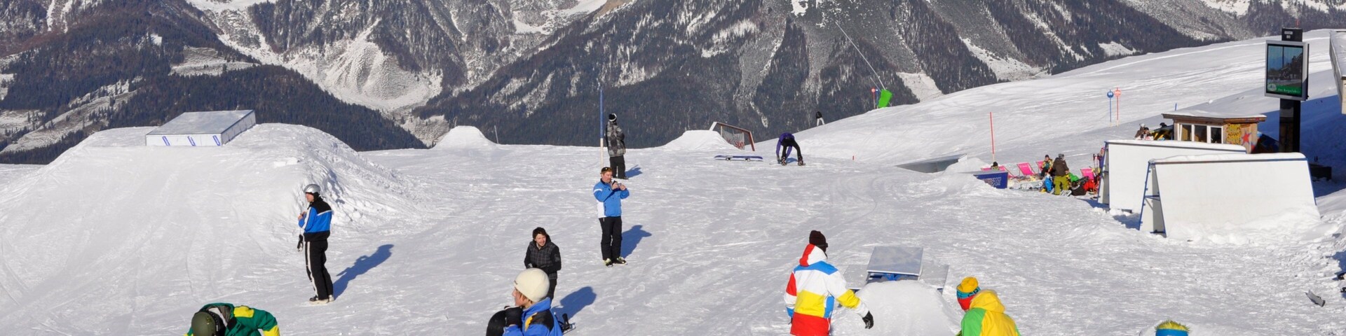 A snowy ski slope with skiers and snowboarders.