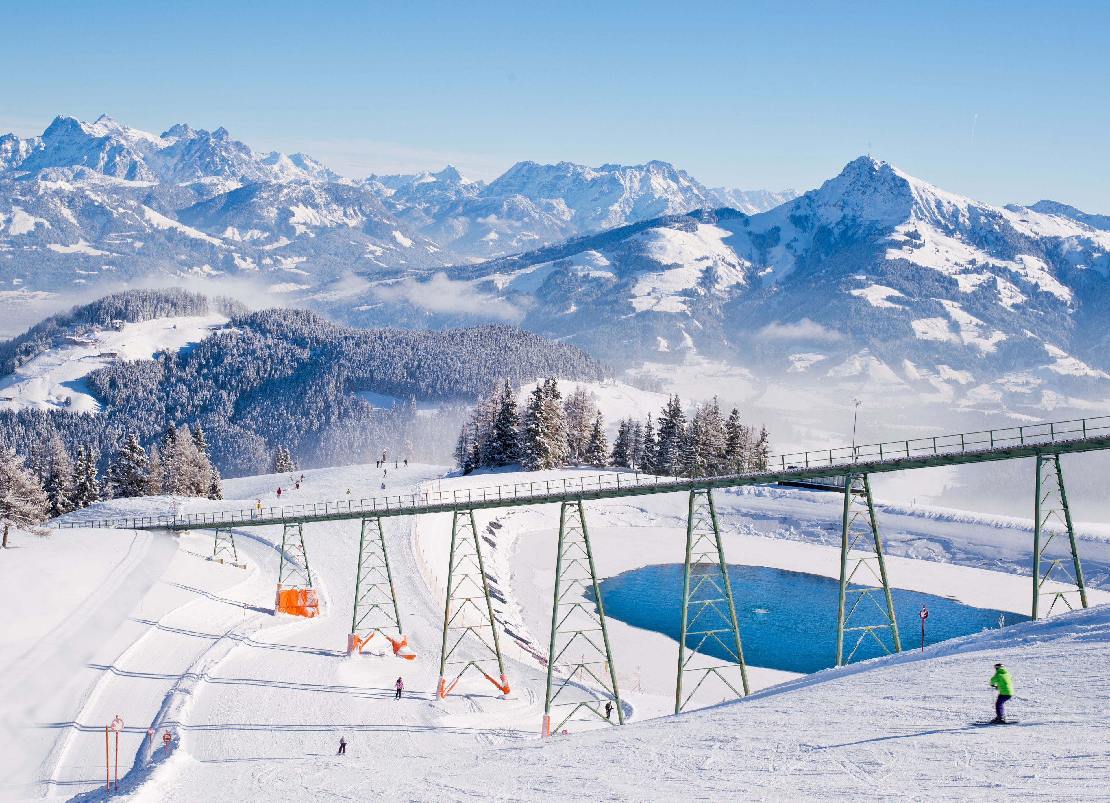 Ski train trail and small lake over Austrian alps