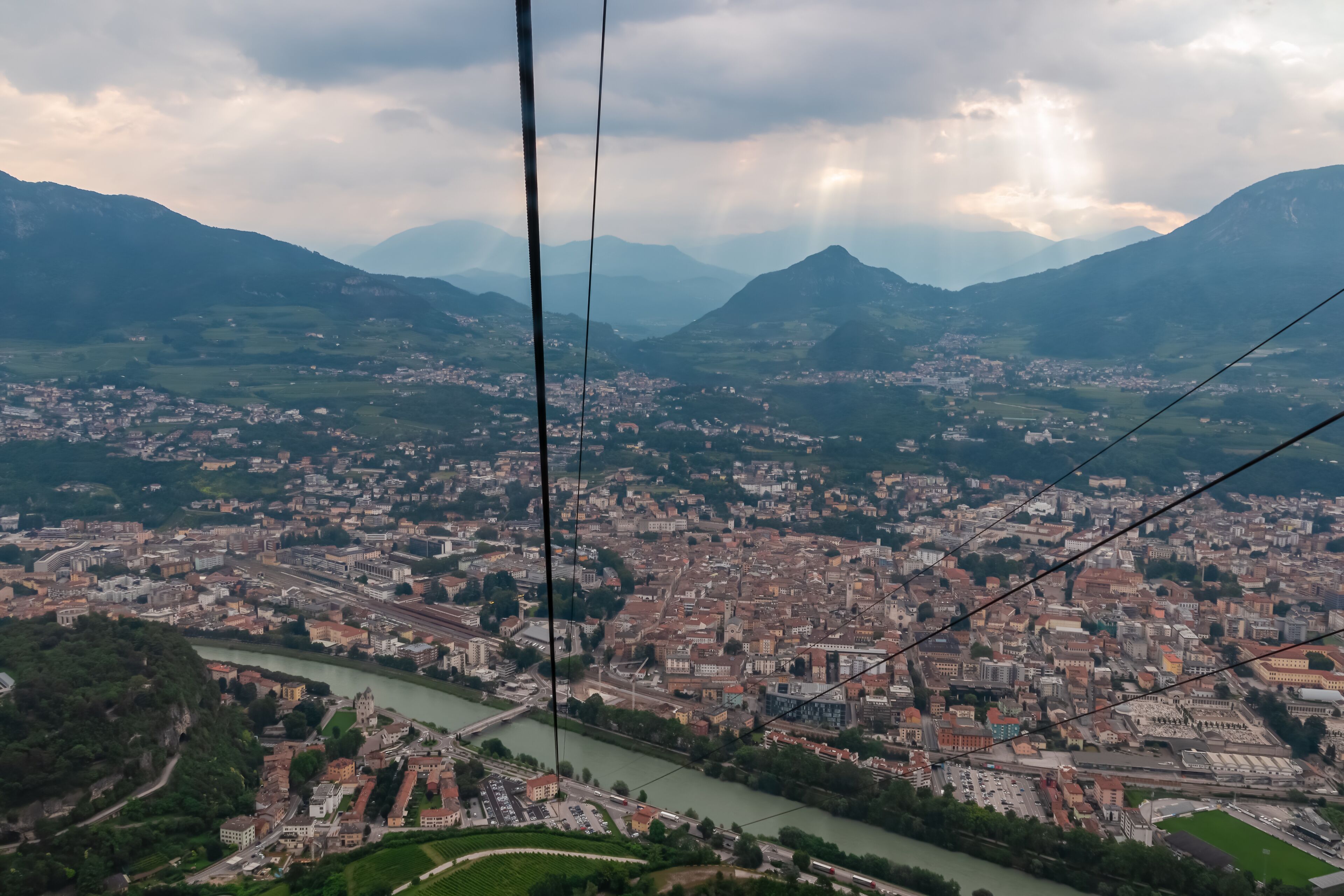 A panoramic view of a city with a river, mountains, and a bridge.