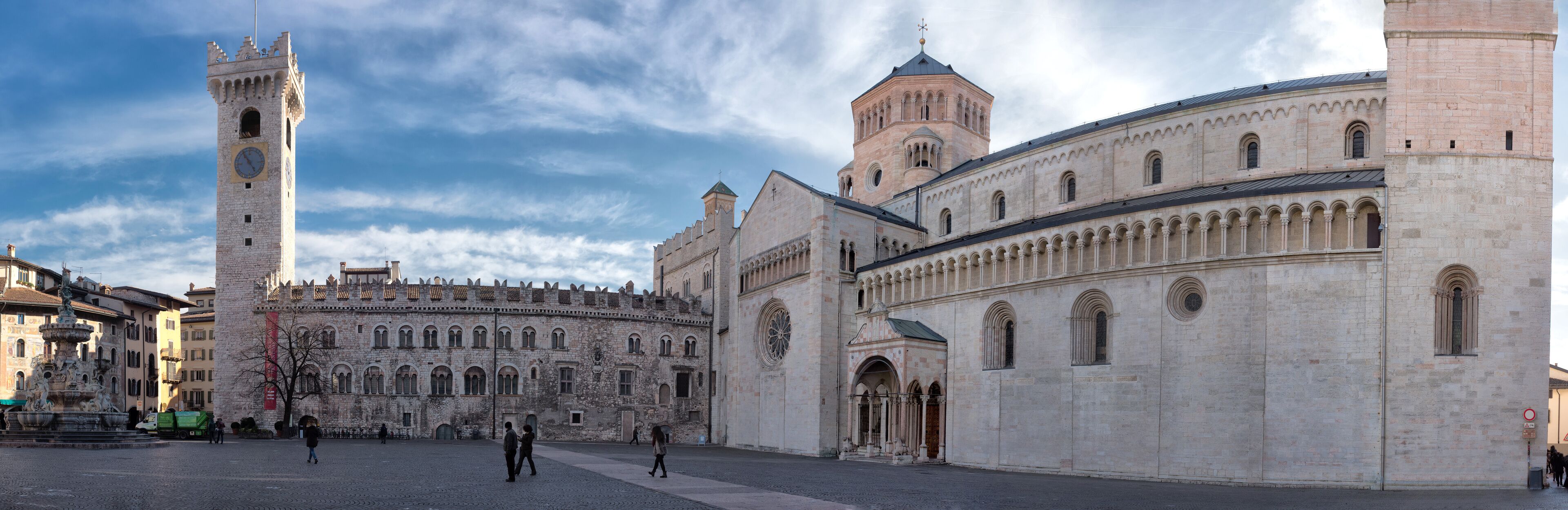 A historic square with a prominent tower, a large cathedral, and a fountain.