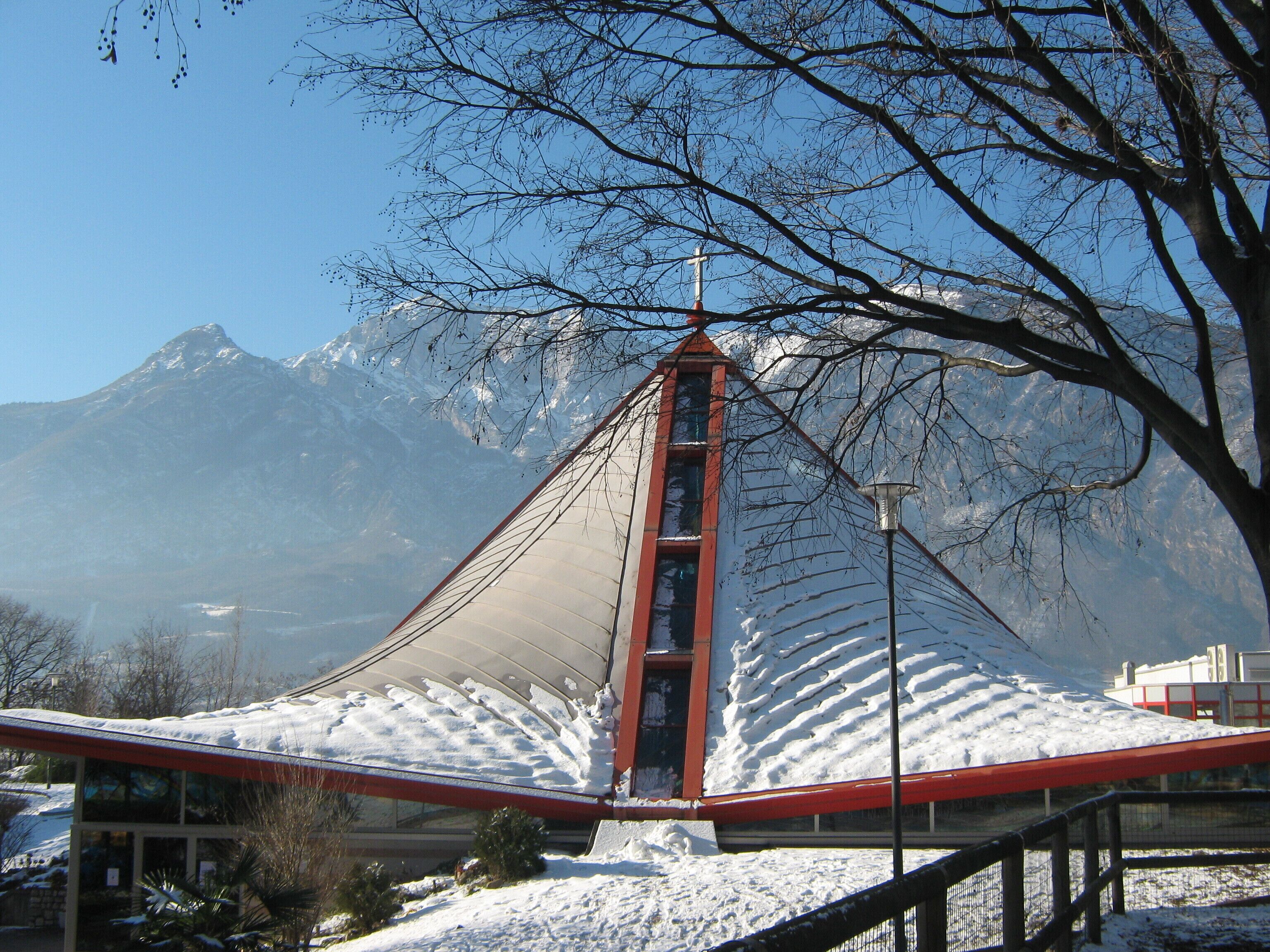 A snow-covered mountain with a church steeple and a red roof.