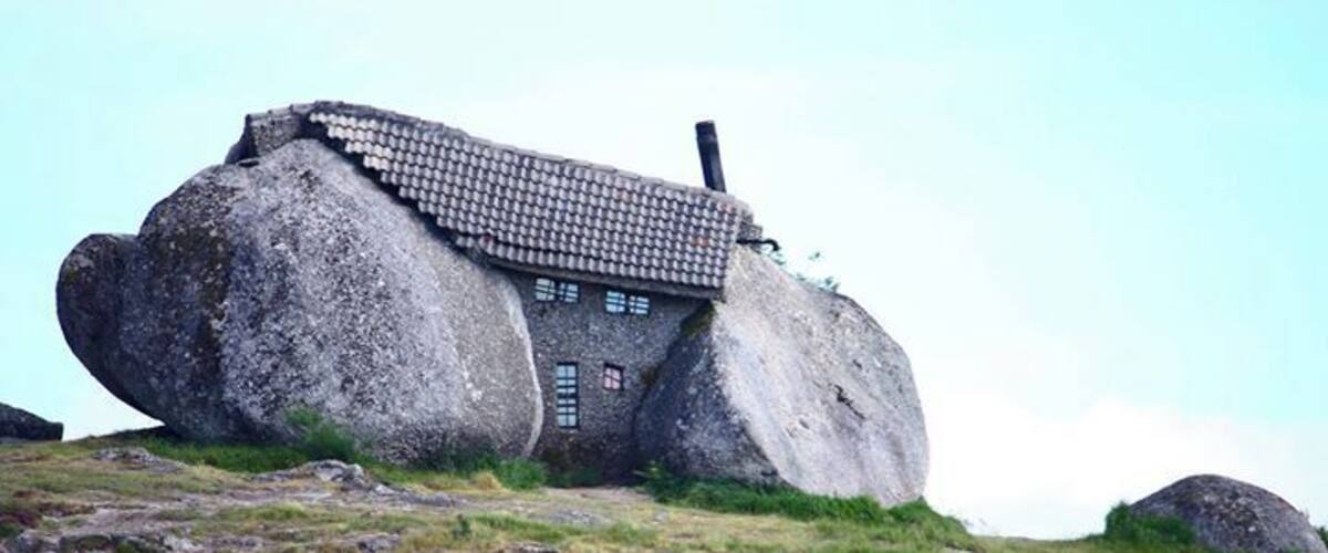 A house built on a large rock formation with a tiled roof.