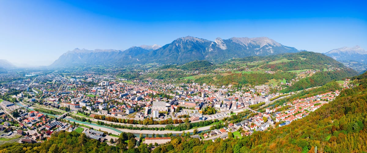 Une vue panoramique d’une ville nichée dans une vallée, avec des montagnes en arrière-plan.