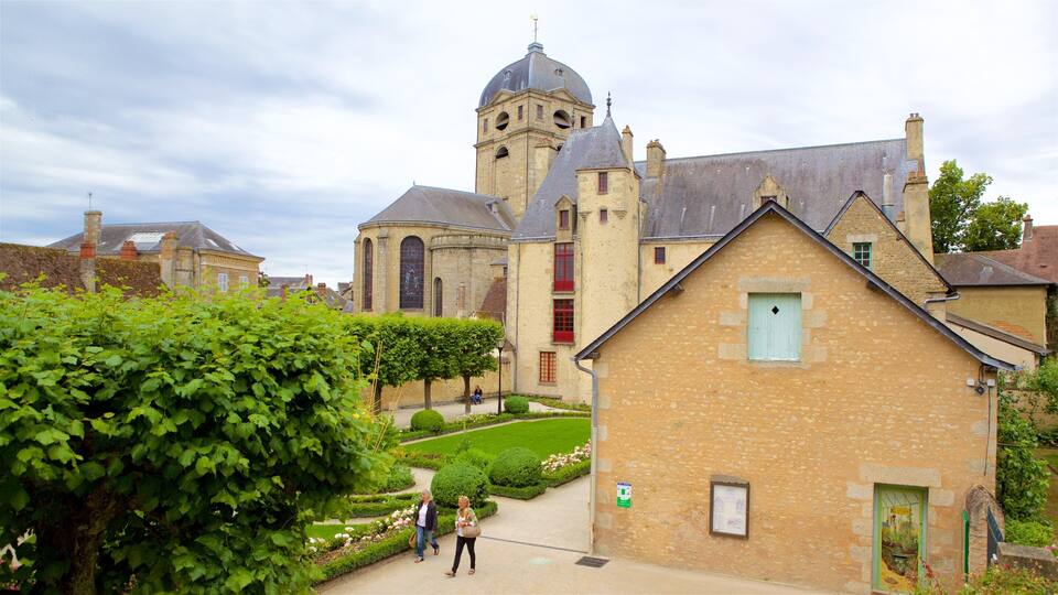A historic church with a bell tower, a courtyard with a hedge, and a small building with a green door.