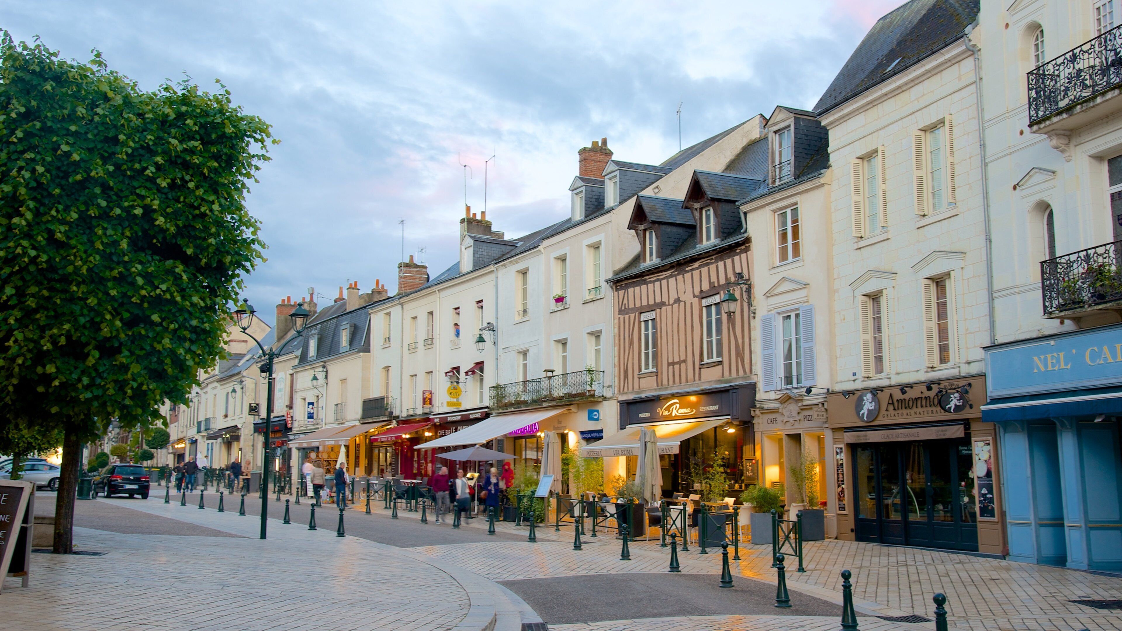 A European street lined with historic buildings, cafes, and outdoor seating areas.