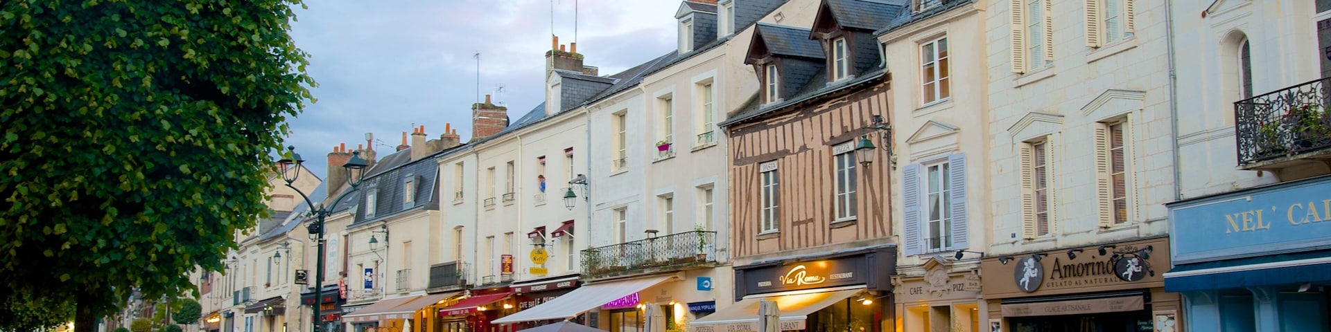A European street lined with historic buildings, cafes, and outdoor seating areas.
