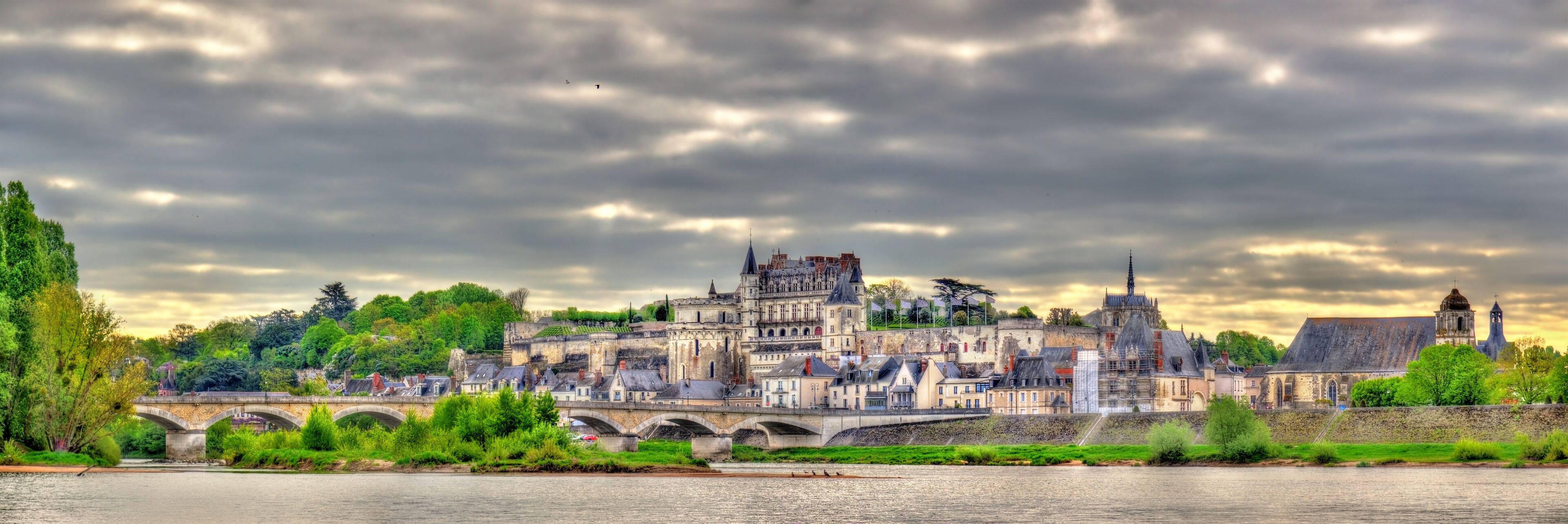 A historic town with a prominent castle, a river, and a bridge.