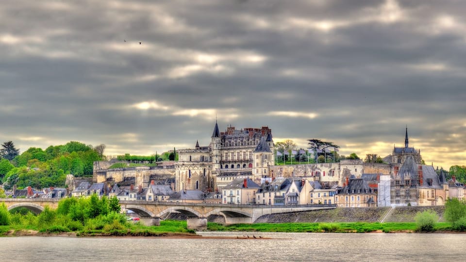 A historic town with a prominent castle, a river, and a bridge.