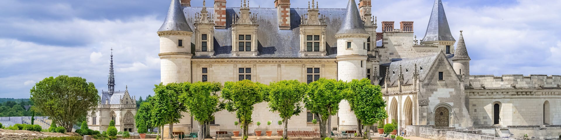 A historic castle with turrets, a courtyard, and a river in the background.