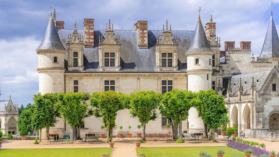 A historic castle with turrets, a courtyard, and a river in the background.