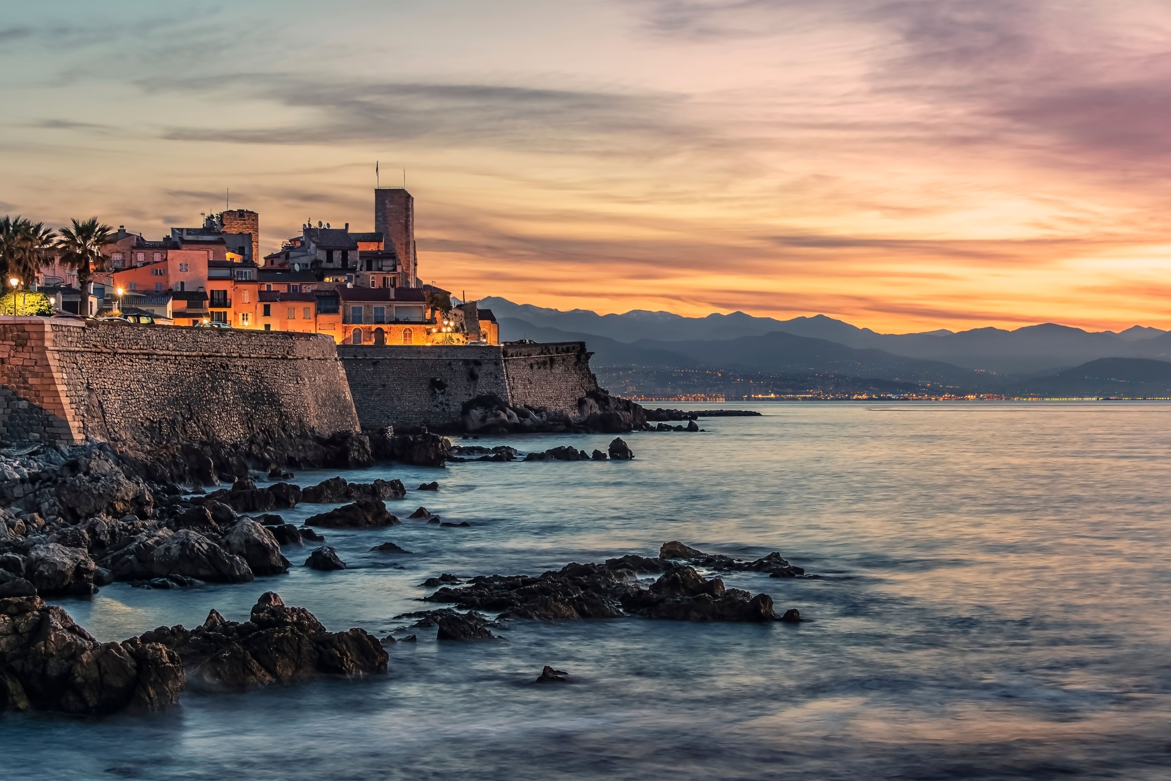 A coastal town with historic buildings and a stone wall overlooking the sea.