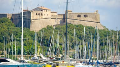 Un castillo histórico en una colina, con un puerto deportivo lleno de veleros abajo.