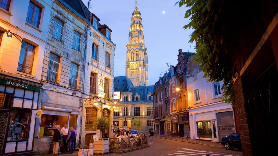A historic European town square with a prominent tower, shops, and pedestrians.