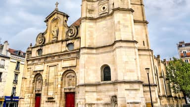 Una iglesia histórica con una alta torre campanario y puertas rojas.