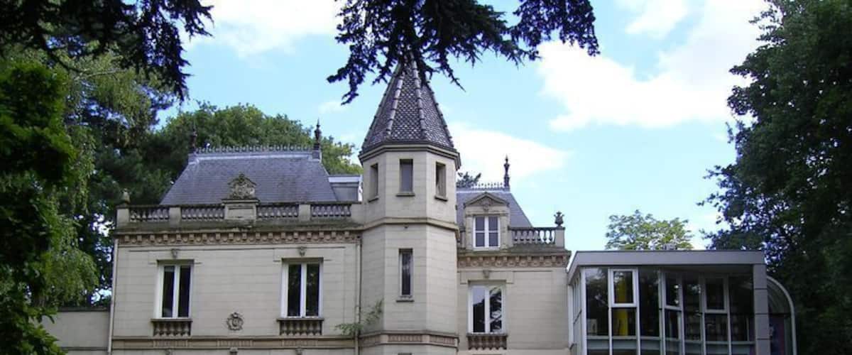 A large, historic building with a turret and a conservatory.